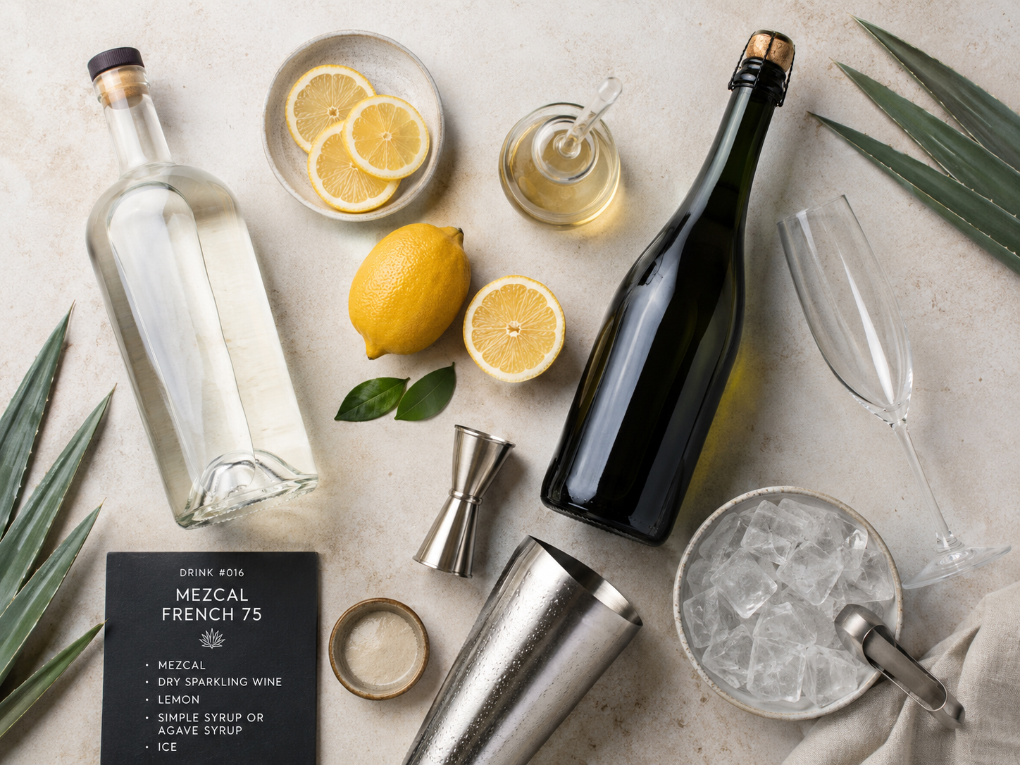 Ingredients and tools for the Mezcal French 75 with mezcal, lemon, syrup, sparkling wine, shaker, flute, ice, and agave leaves.